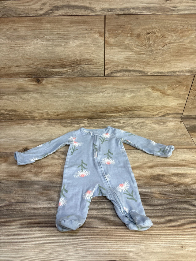 Flat lay of newborn blue floral footed baby sleeper showcasing front zipper and built-in feet with wood floor background