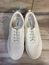Top-down view of Cat & Jack Tyler off-white slip-on canvas sneakers showing elastic lace detail, metal eyelets, and visible size 5 insole on wood floor