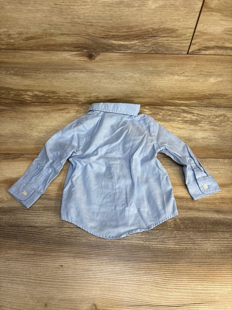 Light blue long sleeve button-up toddler shirt on wood floor, gently used kids clothing