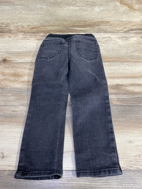 Children's black denim jeans with pockets, laid flat on wooden background