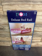 Front view of boxed Dream on Me Deluxe bed rail showing pink mesh safety rail on a child's bed with wood wall background