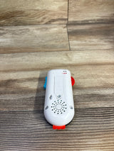 Rear view of Fisher-Price Laugh & Learn Stream & Learn Remote showing battery compartment and speaker grille on wood floor