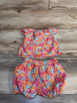 Colorful floral baby outfit with ruffled top and bloomers on wood floor