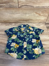 Navy blue short sleeve toddler shirt with yellow and white floral print on wood background
