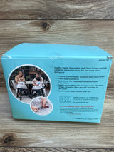 Back of J.L. Childress high chair cover box showing product text, photo of covers on chairs, and strap buckle on wood surface