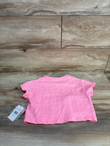 Back view of NWT Freestyle Revolution cat purse shirt in solid pink with hangtag attached on wood plank floor