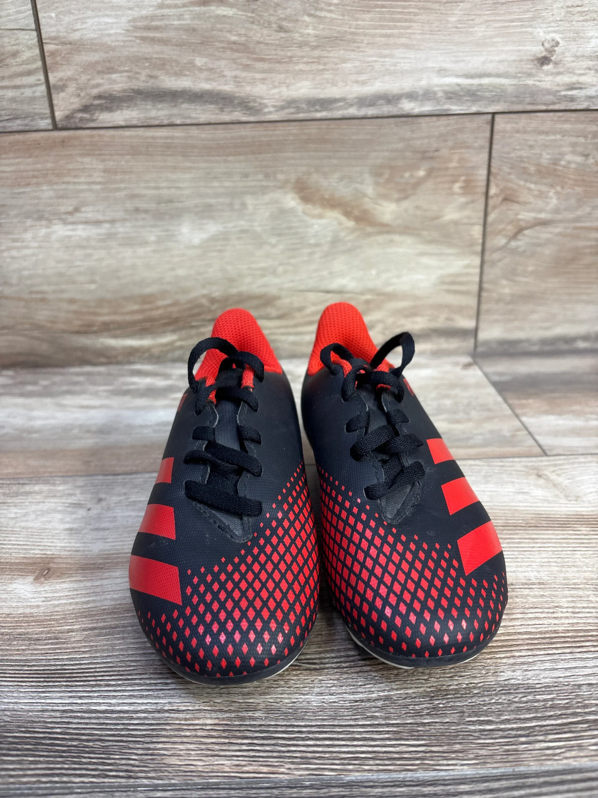 Front view of Adidas Predator 20.4 toddler soccer cleats size 12C, black with red accents and textured forefoot on wood floor