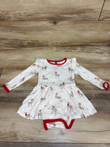 Top-down view of white Kyte Baby Bamboo Cloud Deer Twirl Bodysuit Dress with red trim, deer print, attached bodysuit, and wood background