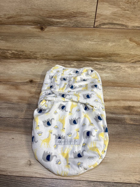 Top view of Petite L’amour plush swaddle wrap showcasing white plush fabric with giraffe, elephant, and bee print on a wood background