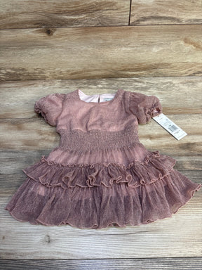 Pink toddler dress with puff sleeves and ruffled skirt on wooden floor