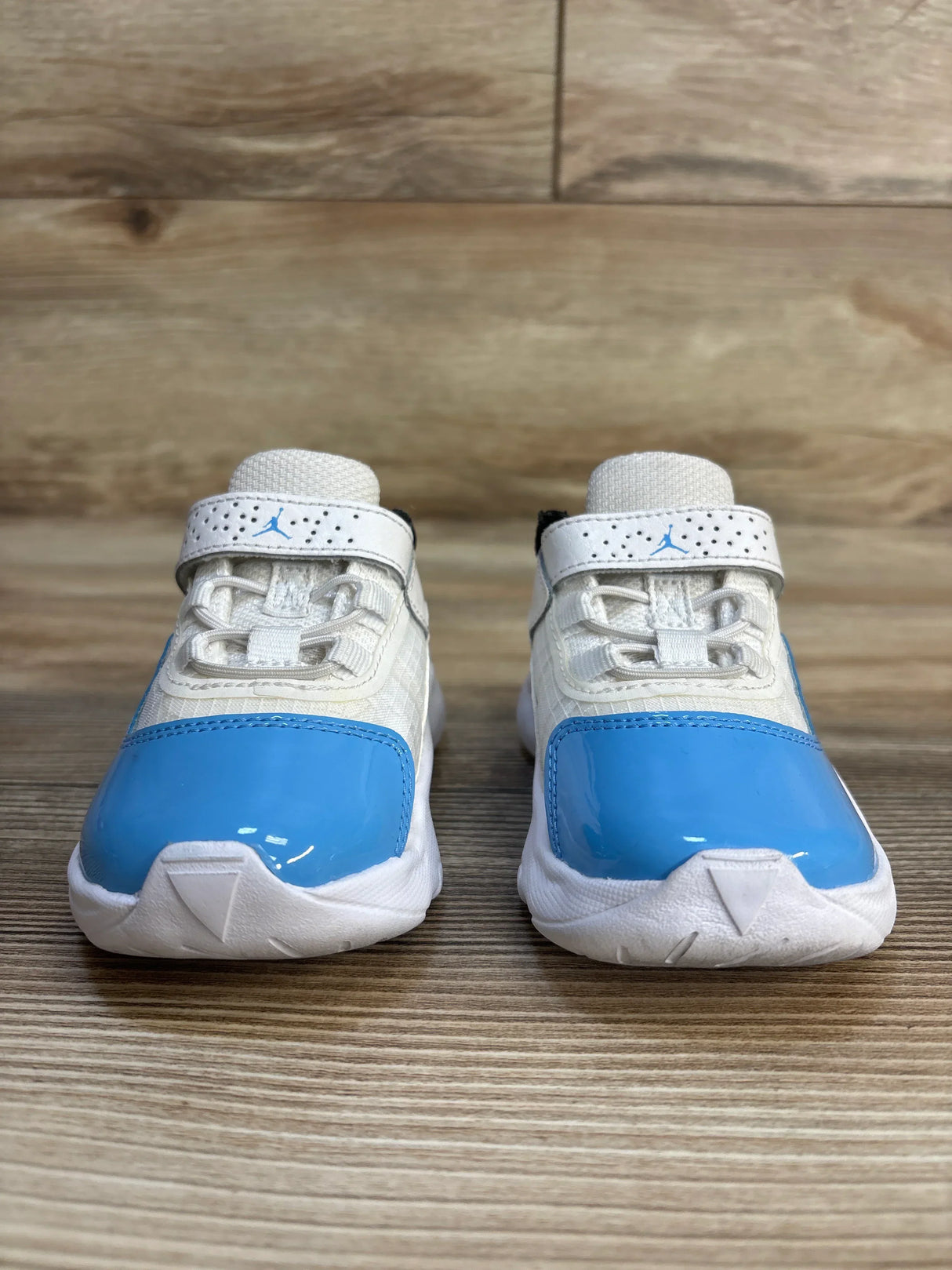 Toddler white and blue athletic sneakers with velcro straps on a wooden surface
