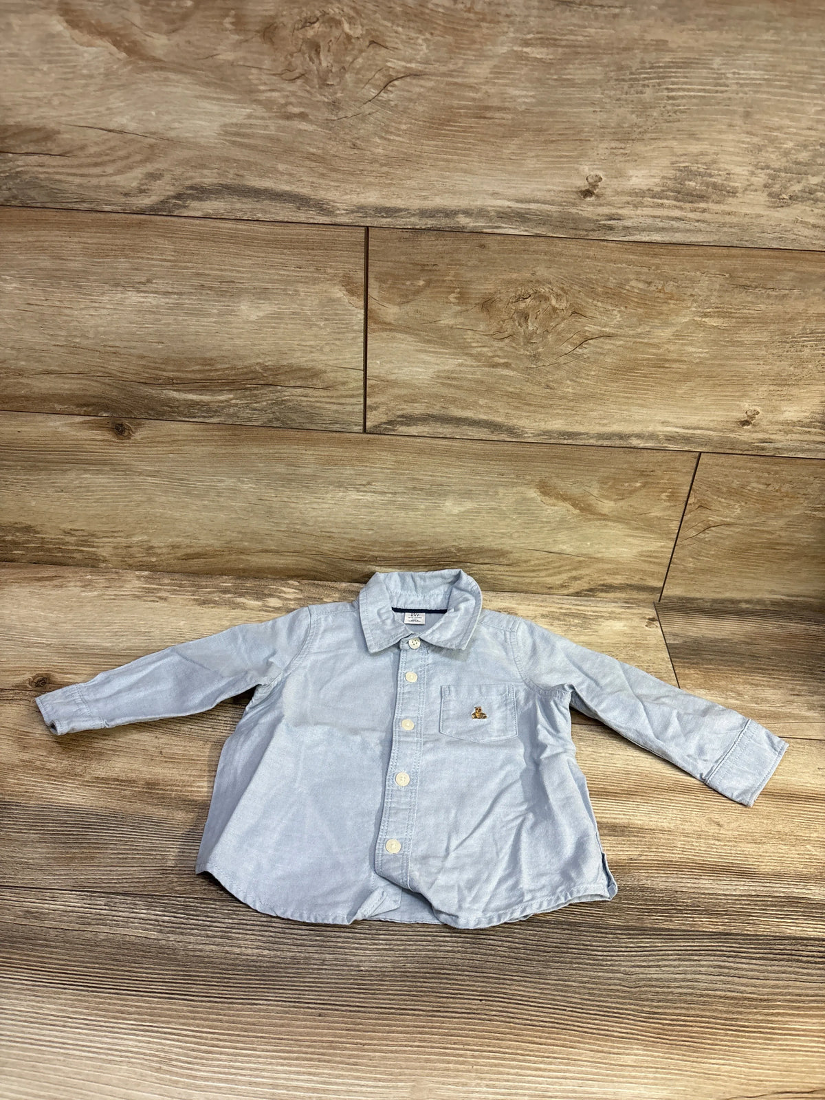 Baby Gap light blue button-up shirt for infants size 12-18 months on a wooden background