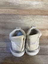 Cream and silver baby sneakers on wooden floor, gently used kids footwear