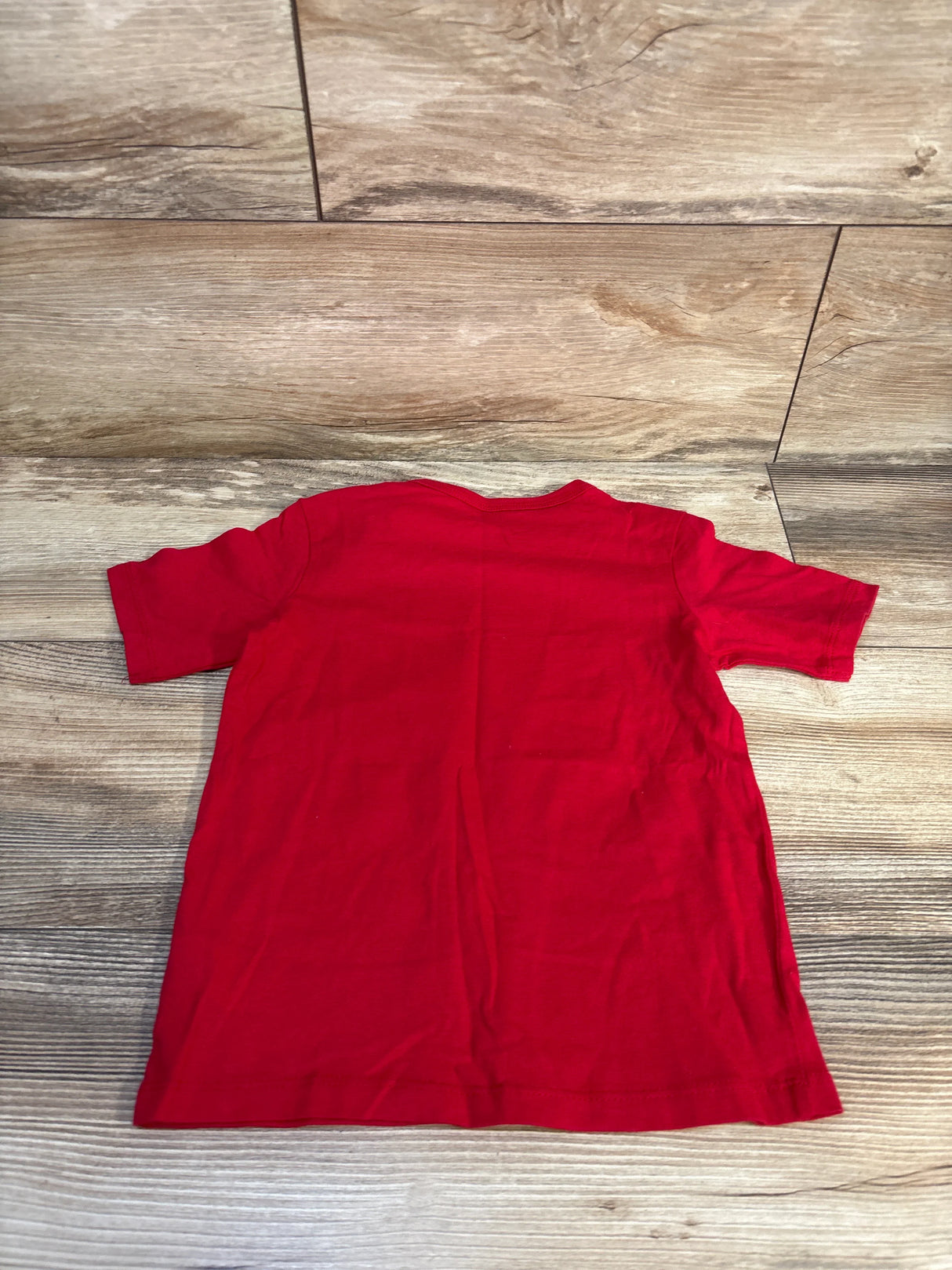 Red short sleeve toddler t-shirt laid flat on wood floor