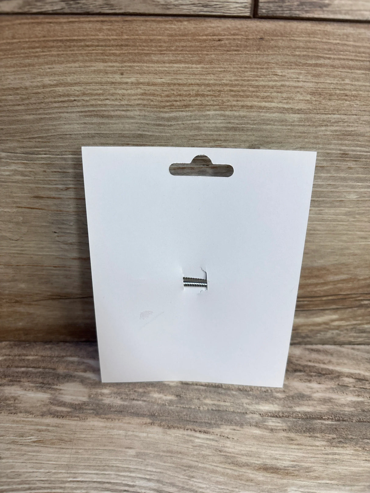Front of 1st birthday hair bow display card (bow removed) showing hang slot and silver elastic loop on wood background