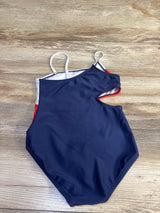 Flat lay of girls' red white and blue one-piece swimsuit showing front with side cut-out and white straps on wood background