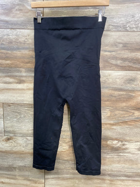 Black high-waisted leggings hanging on wood background, cropped length pants