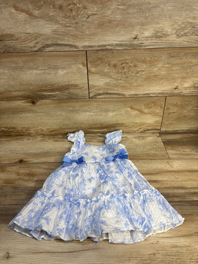 Blue and white floral print baby girl dress with bows on rustic wood floor