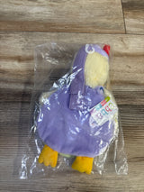 Top-down view of Mother Goose plush book showing purple cover, yellow plush feet and tag, in clear plastic bag on wood background