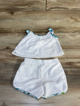Flat lay of Janie and Jack two-piece terry set in white showcasing tank top and shorts with blue green floral trim on wood plank floor