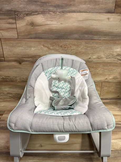 Front view of Ingenuity Keep Cozy 3-in-1 bouncer, rocker and toddler seat with gray padding and elephant toy on wood planks