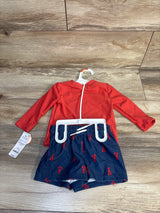 Kids' red rash guard with navy lobster print swim shorts on wood background