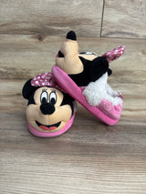 Pair of pink Minnie Mouse plush slippers for kids on wooden floor, featuring polka dot bow and fuzzy lining