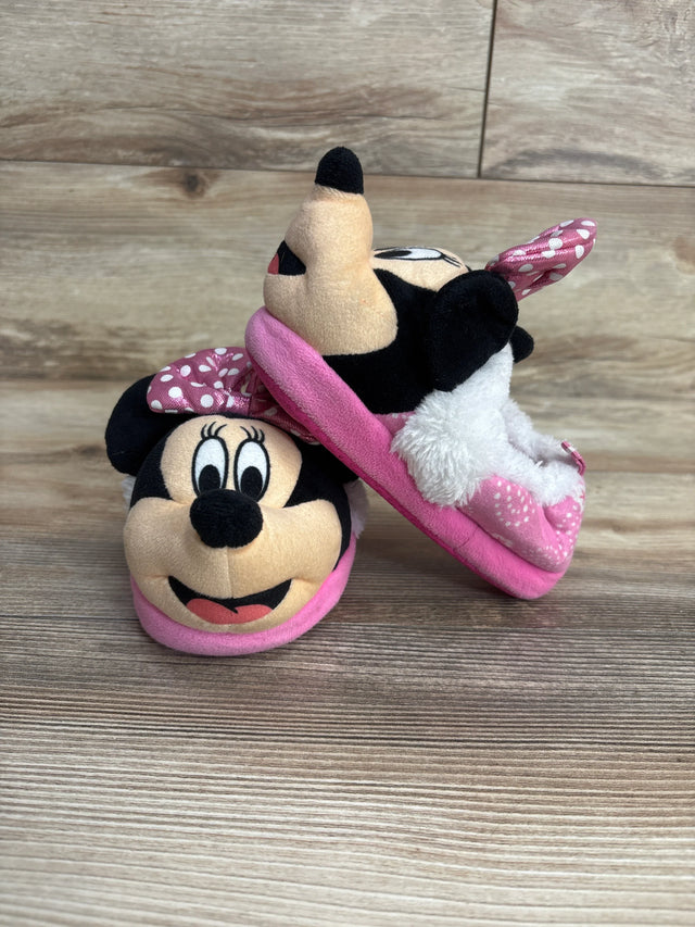 Pair of pink Minnie Mouse plush slippers for kids on wooden floor, featuring polka dot bow and fuzzy lining