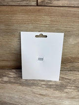 Front view of white display card for donut applique glitter hair bow showing attached silver two prong hair clip on wood background