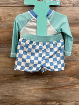 Kids long sleeve swim shirt and blue checkered swim trunks on wood background