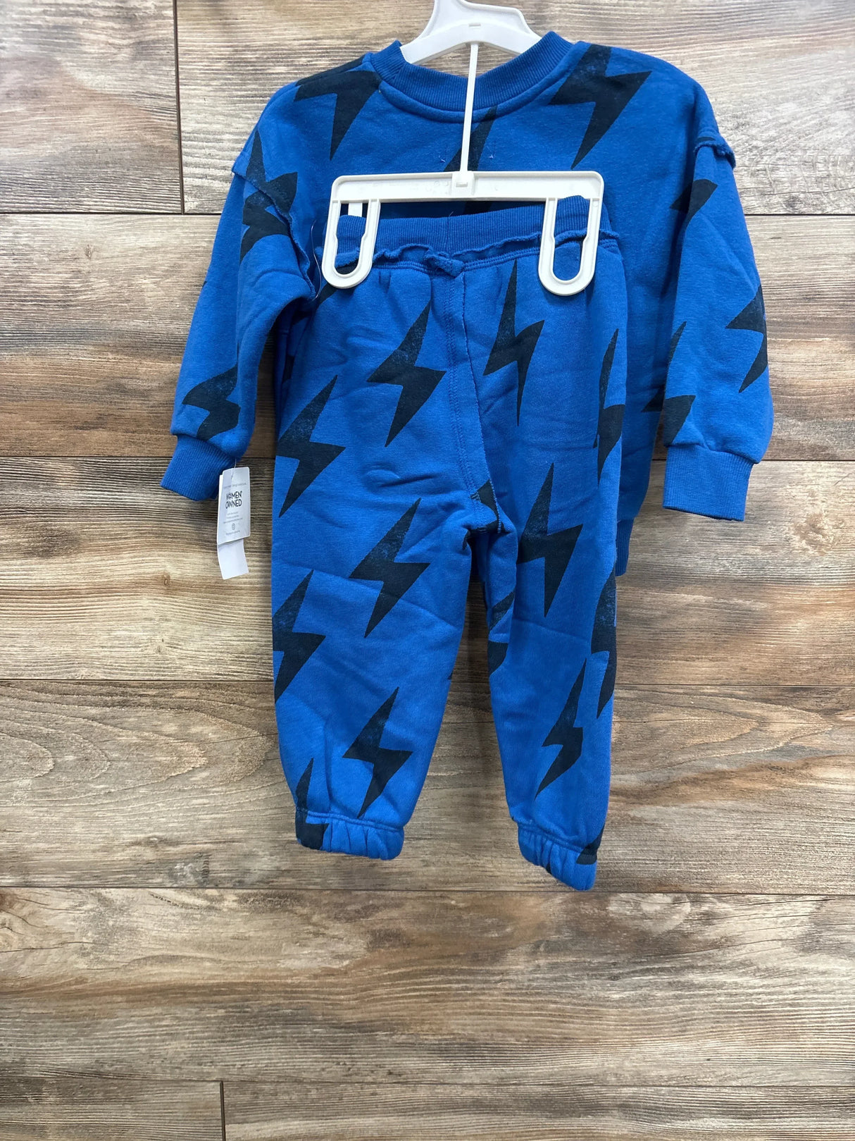 Blue toddler sweatshirt and pants set with black lightning bolt print on wooden background
