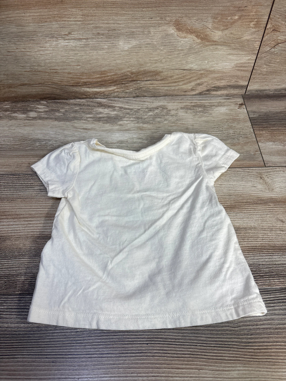 Back view of Baby Gap x Disney Minnie Mouse ivory toddler T-shirt showing puff sleeves and crew neck on wood floor