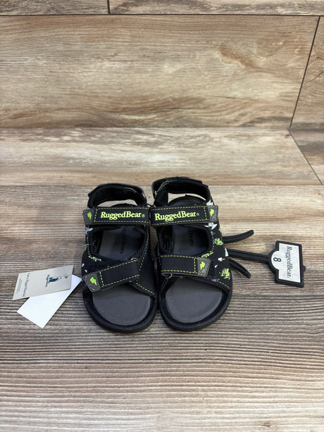 Front view of RuggedBear black open-toe kids sandals with two Velcro straps and lime-green logo accents on wood background