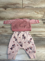 Pink toddler outfit with fuzzy sweatshirt and Minnie Mouse patterned pants on wood background