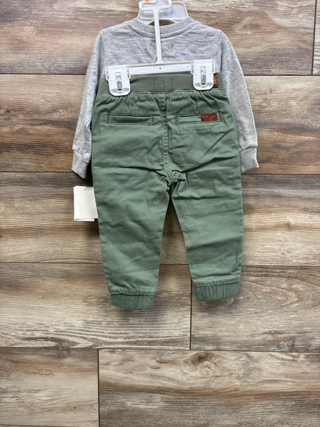 Back view of baby henley shirt and pants set showing grey henley top and olive-green pants with elastic waist on wood floor