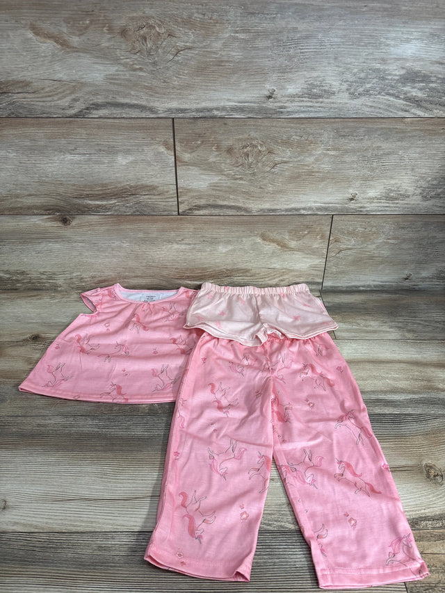 Flat lay of pink 3-piece unicorn pajama set showing ruffled top, elastic-waist shorts and pants on wood background