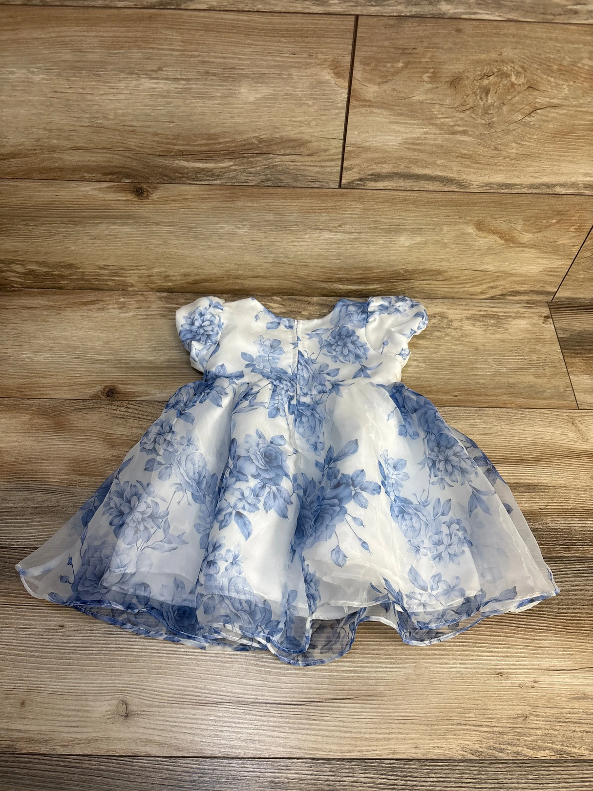 White and blue floral baby dress with puff sleeves on wood floor