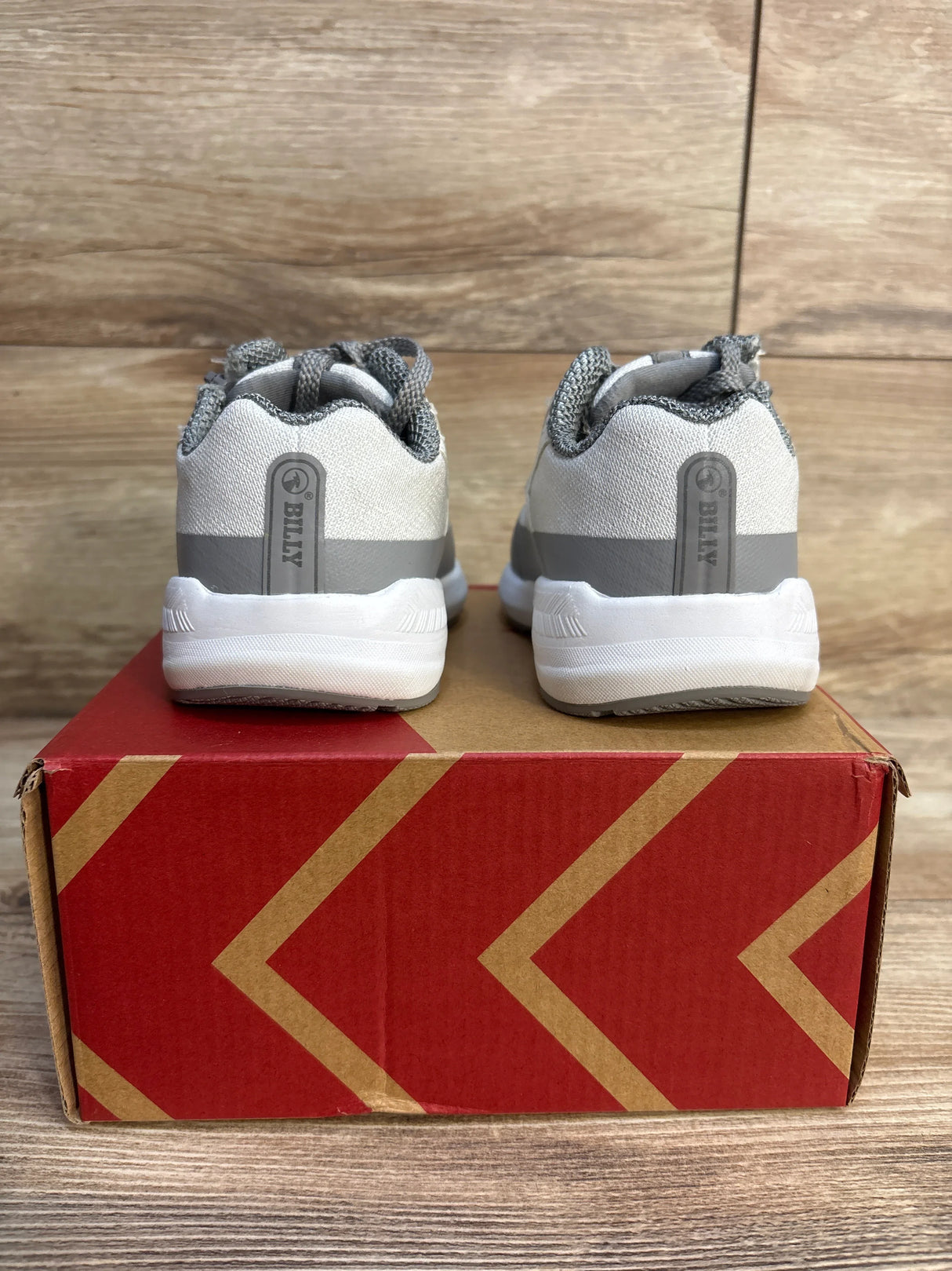 Gray and white kids sneakers with mesh detail, shown from the back on a red shoe box