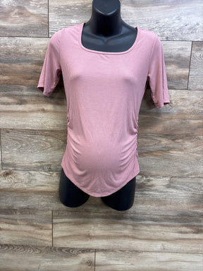 Front view of Sonoma maternity ruched short sleeve shirt in pink showcasing side ruching and rounded hem with wood-look background