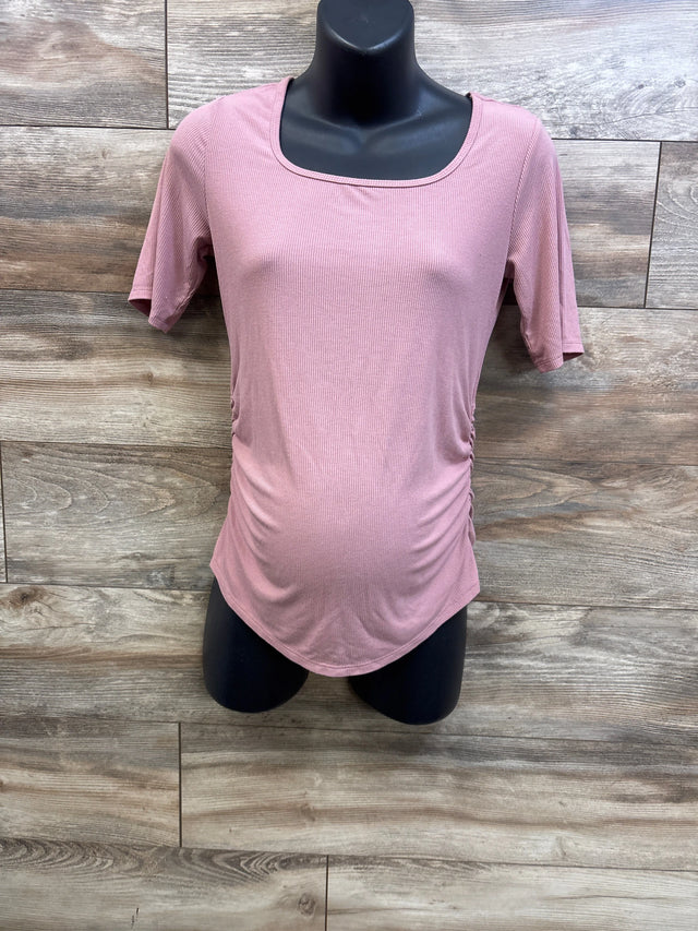Front view of Sonoma maternity ruched short sleeve shirt in pink showcasing side ruching and rounded hem with wood-look background