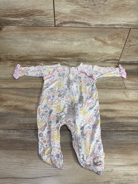 Floral patterned baby sleeper with footies and pink ruffle details laid on wooden floor