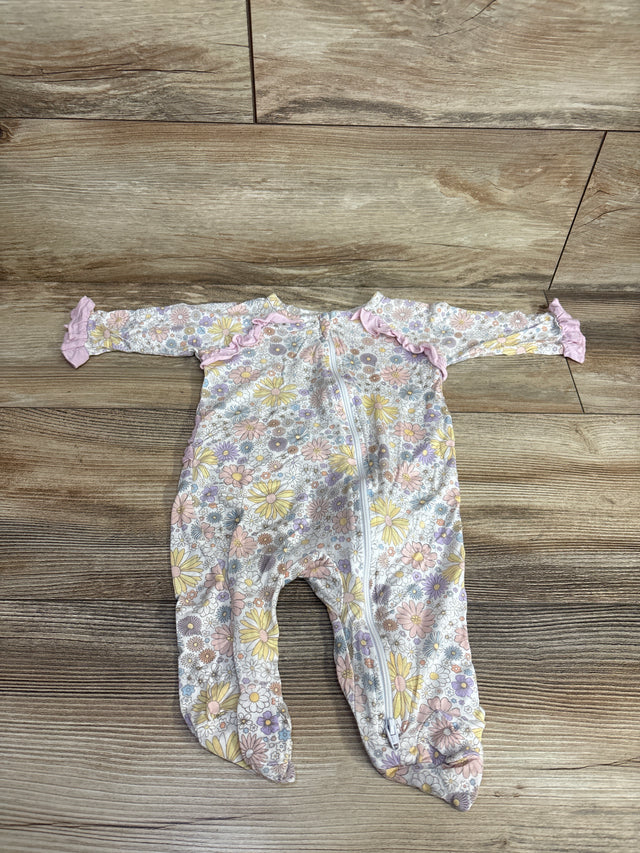 Floral patterned baby sleeper with footies and pink ruffle details laid on wooden floor