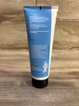Back view of Sharkey's Swimmers After Swim body wash 6 oz showing directions text on blue tube against a wood background