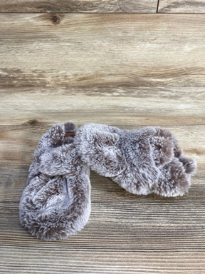 Pair of soft gray faux fur slippers on wooden floor background