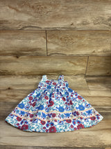 Flat lay Btween girls' white sleeveless dress, blue and red floral print, gathered bodice and full skirt on wood floor