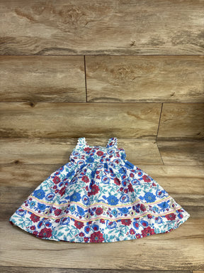 Flat lay Btween girls' white sleeveless dress, blue and red floral print, gathered bodice and full skirt on wood floor