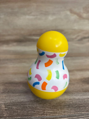 Colorful plastic baby toy with yellow ends and multicolored patterns on wood surface