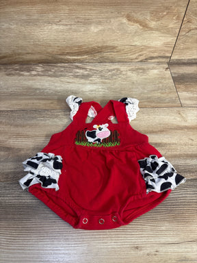 Front view of red newborn bubble romper with embroidered cow, eyelet ruffle straps and cow-print side ruffles on wooden floor