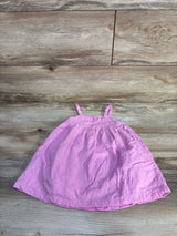 Flat lay of Baby Gap pink embroidered dress 18 to 24 months showing floral eyelet embroidery, gathered bodice and thin shoulder straps on wood background