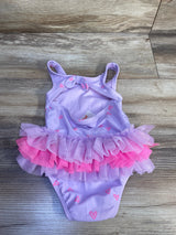 Flat-lay of purple one-piece toddler swimsuit with layered pink and lavender tulle tutu and pink heart print on wood floor